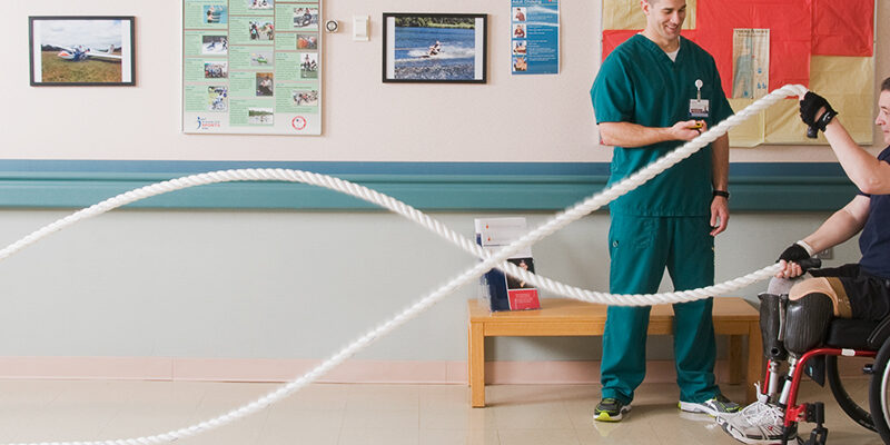 Amputee patient in a wheelchair using exercise ropes