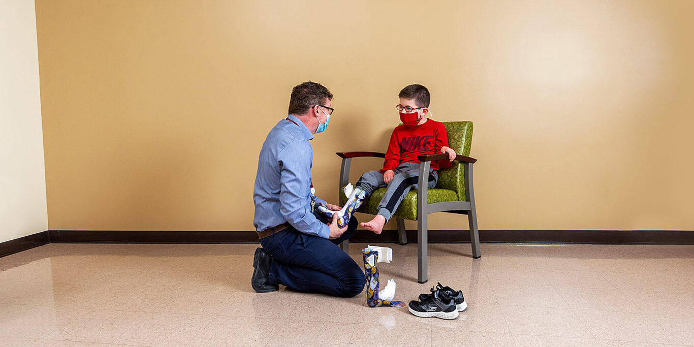 Prosthetist fitting prosthetic leg onto boy